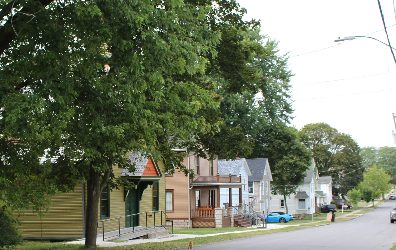 A black and white photograph of a church and row of houses, looking up a street.