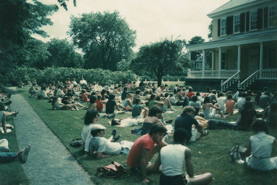 crowd seated on chairs and blankets on lawn to watch concert, with 50th anniversary logo