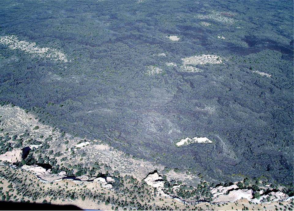 aerial photo of landscape with lava flow with small areas in the field not covered by lava