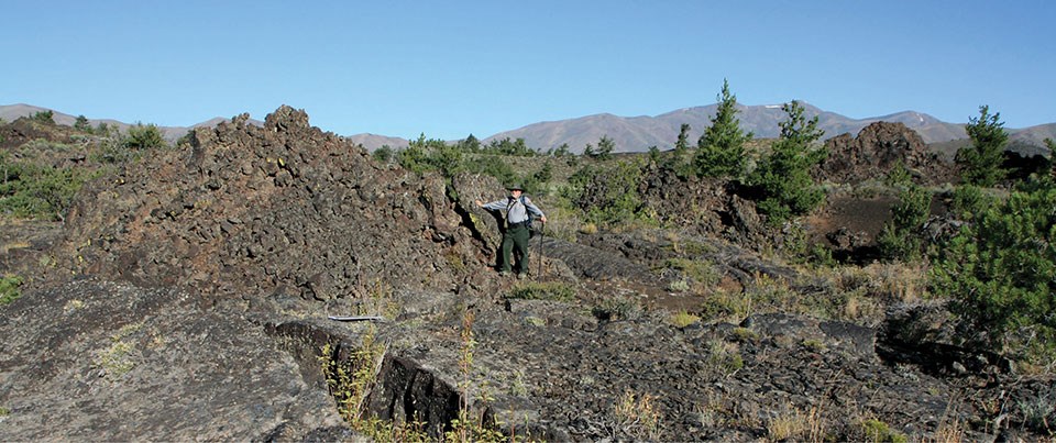 photo of a person standing in a rough lava field next to a raised blocky ridge