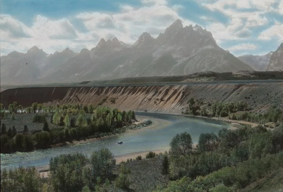 Black and white photo looking across a winding river to a mountain range.