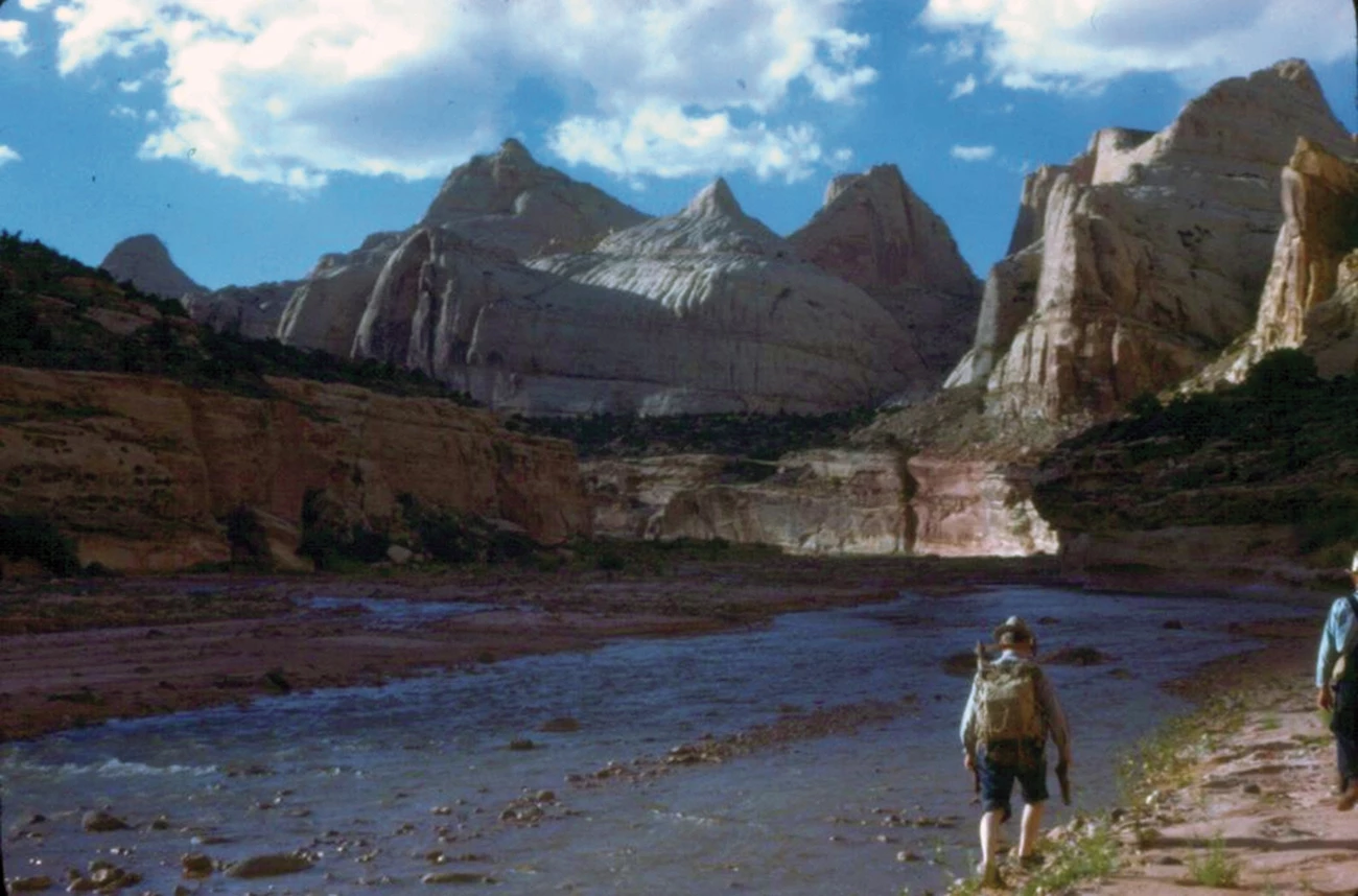 A shallow river flows below majestic desert mountain formations.