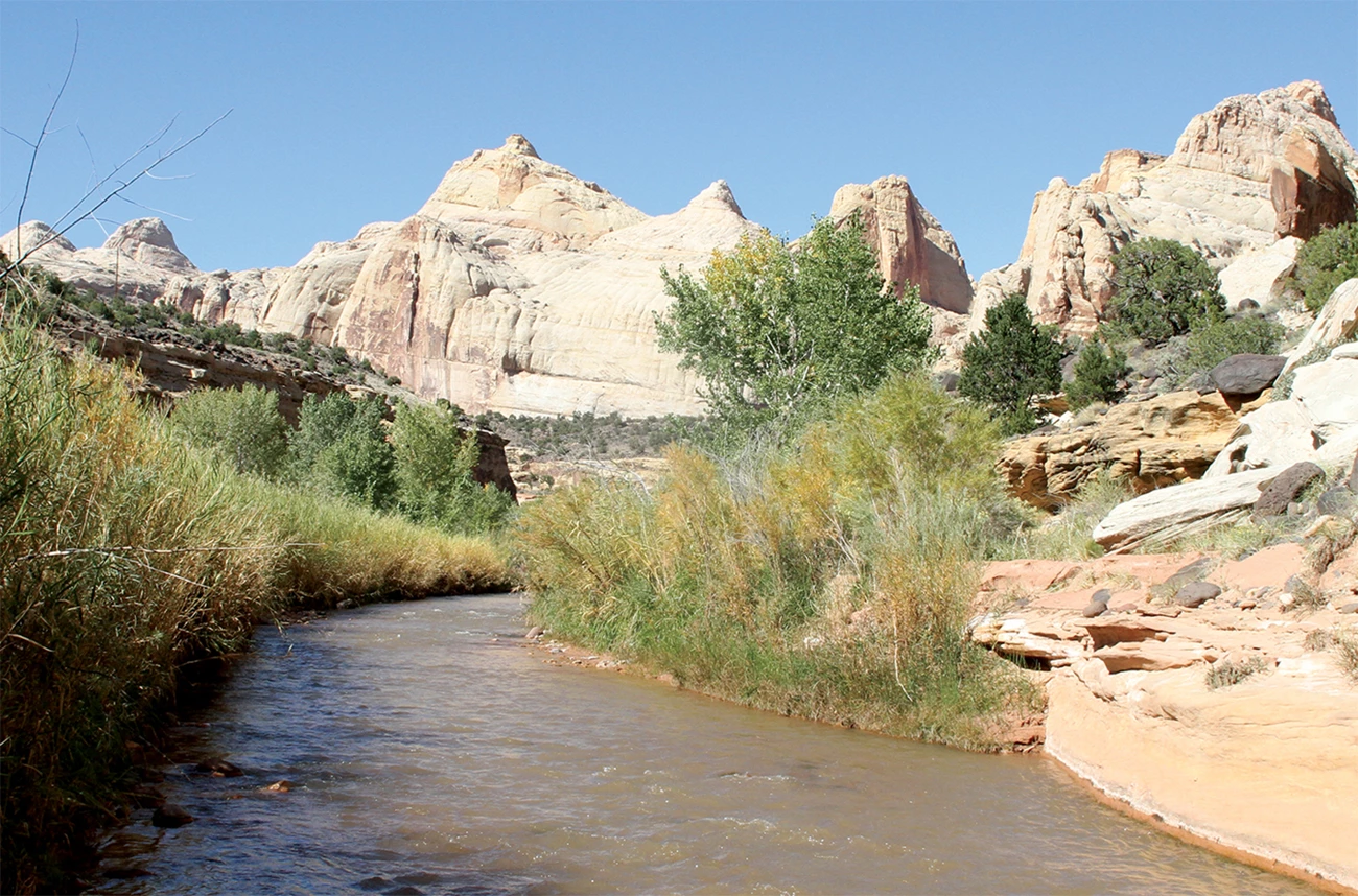 A shallow river flows below majestic desert mountain formations.