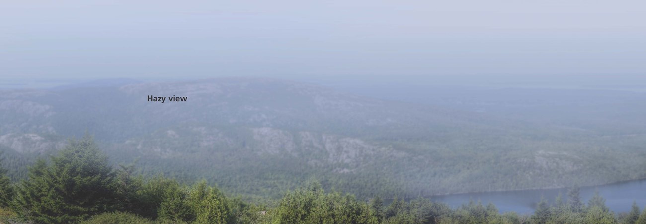 A view from the mountain with pine trees, exposed granite, and a lake visible. The sky is gray and landmarks in the distance grow increasingly obscured the further they are through the hazy air. Text reads: hazy view
