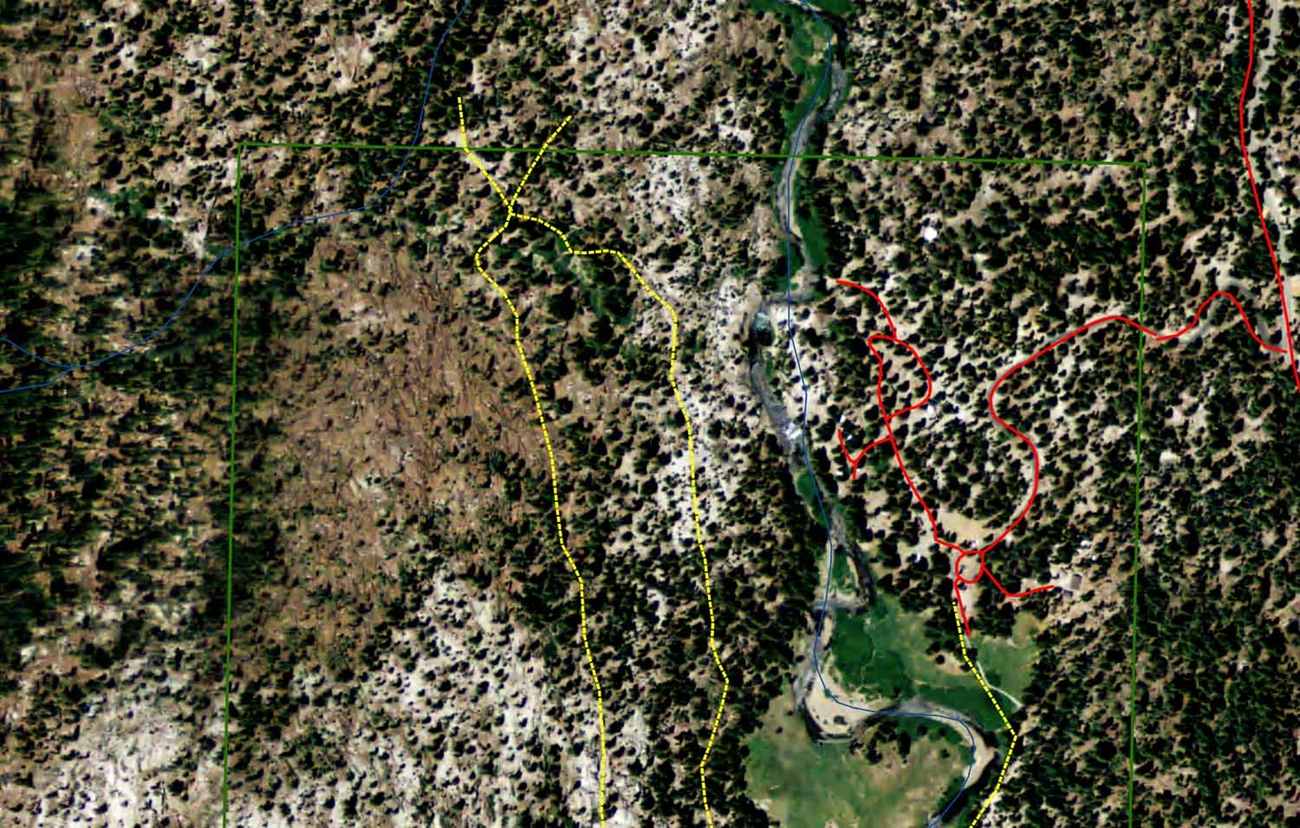 The pre-blowdown aerial image shows a meadow and river channel and forested areas on either side of the meadow.Lines representing roads and trails are shown.