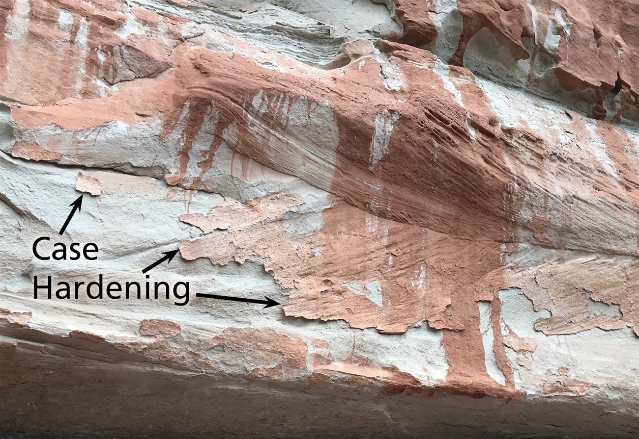 Photo of rock overhang with red streaks and text "cast hardening".