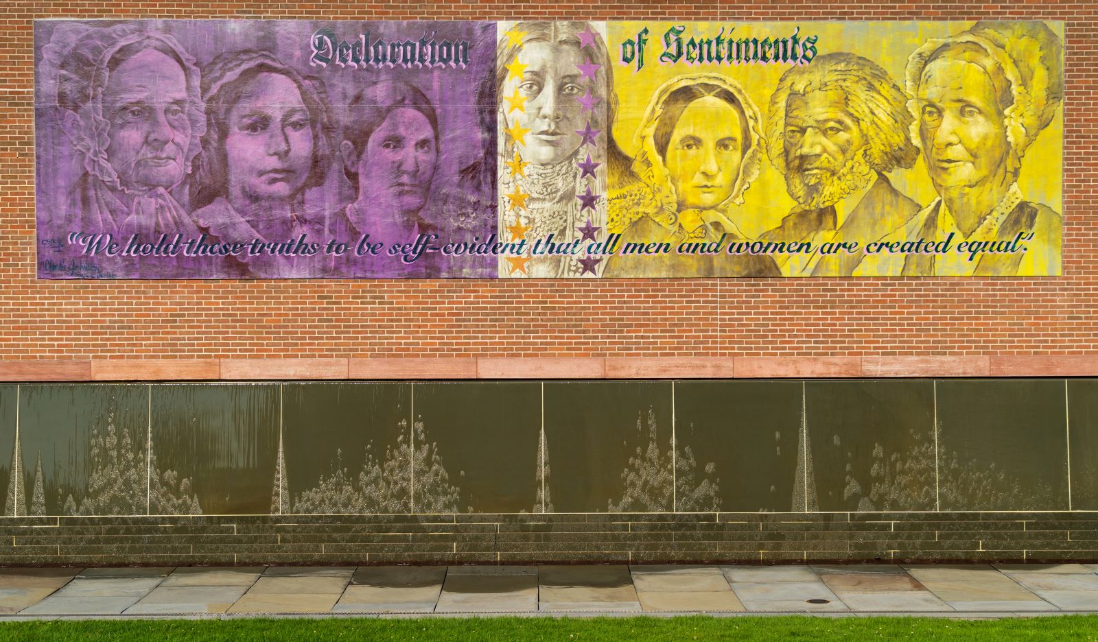 A large purple and gold mural with portraits of women on a brick wall A large purple and gold mural with portraits of women on a brick wall