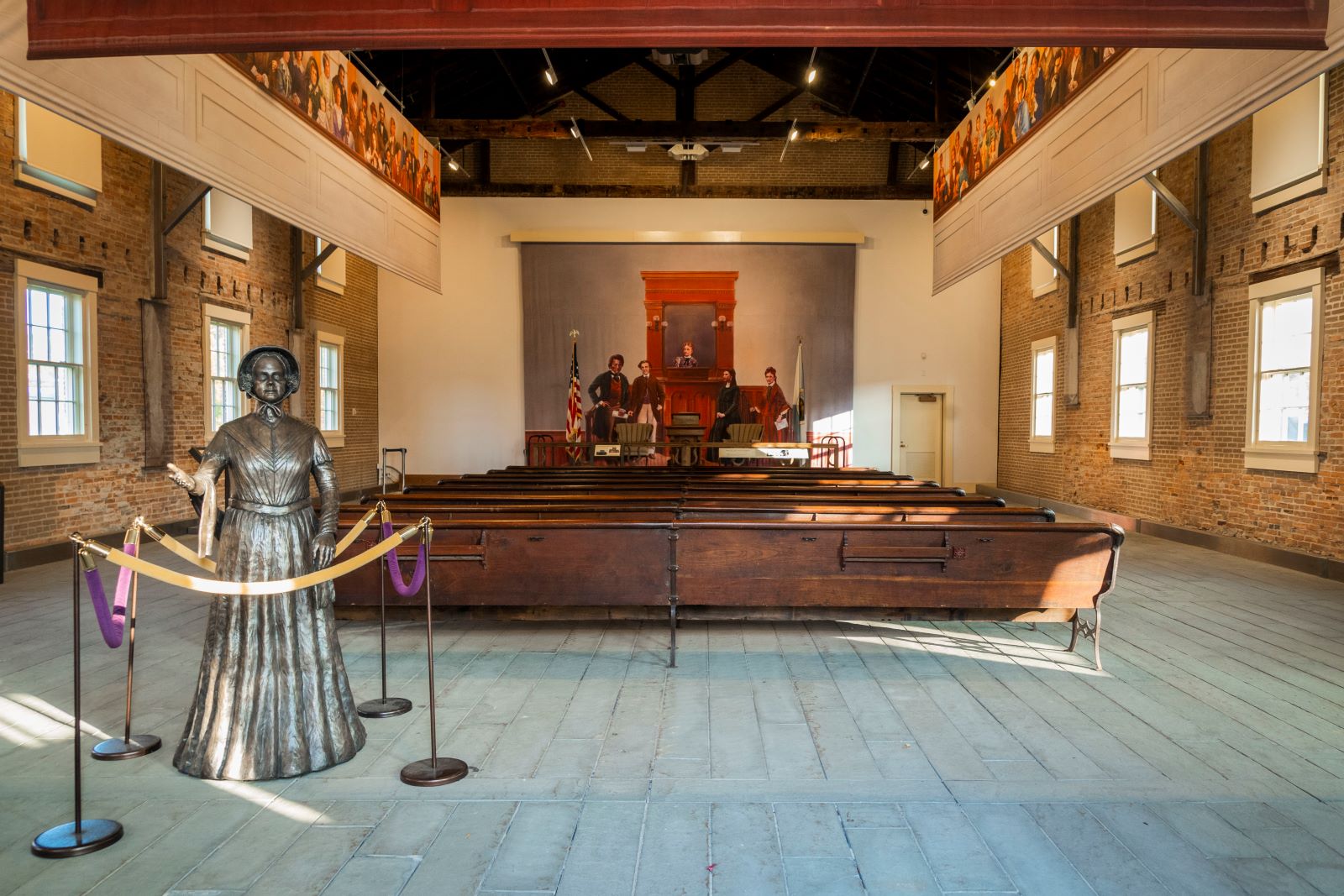 A large room with wooden benches and a bronze statue of a woman A large room with wooden benches and a bronze statue of a woman