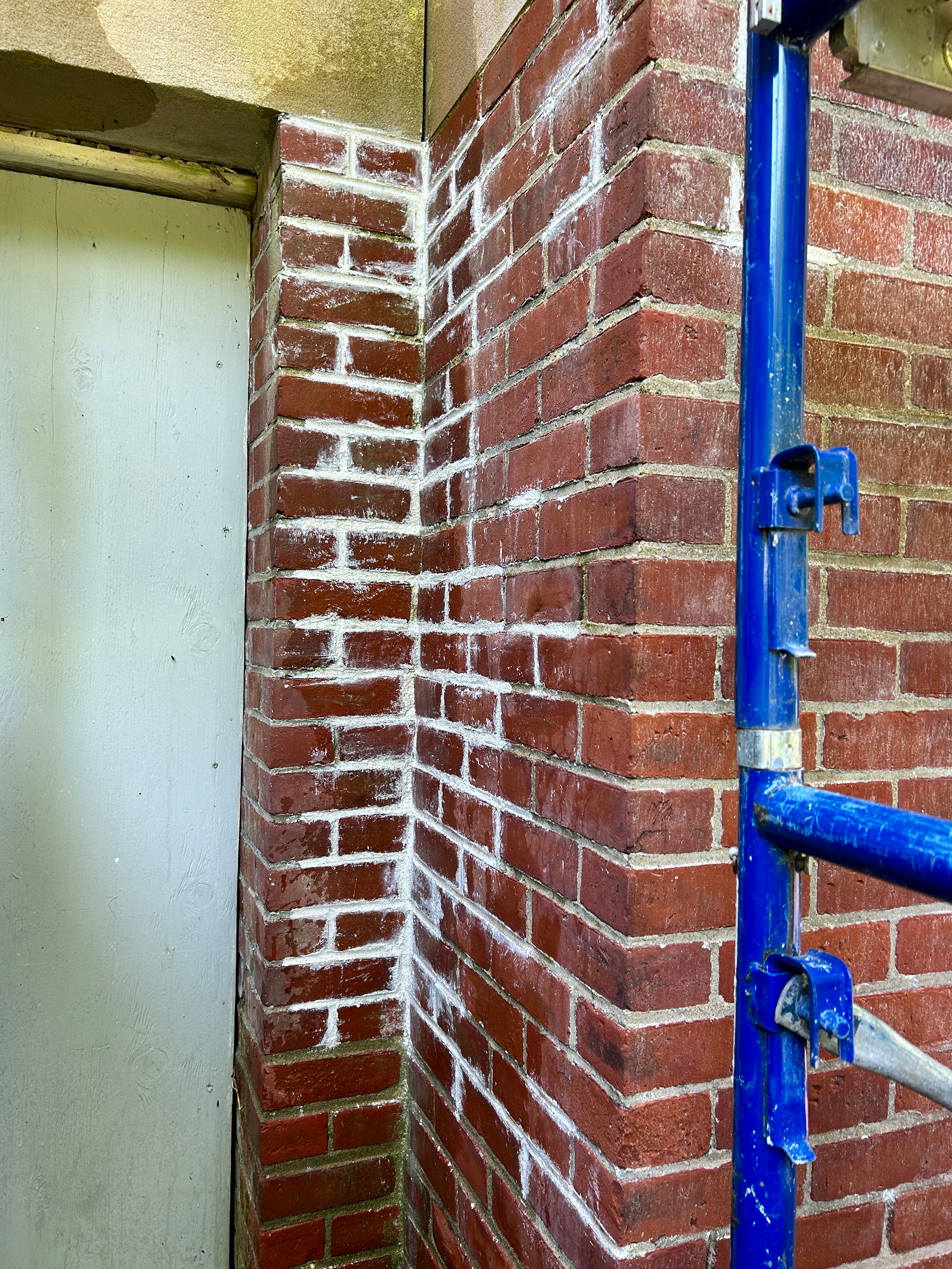 A corner where two old brick walls meet. Much of the mortar has crumbled, leaving empty spaces between the bricks.