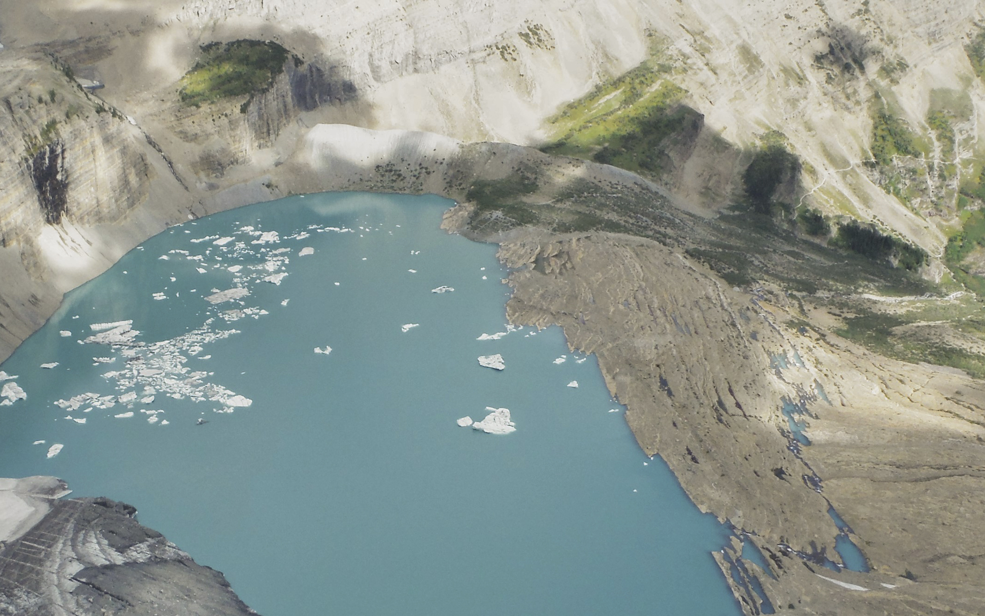 A grainy historic color photo of Grinnell Glacier from high above.