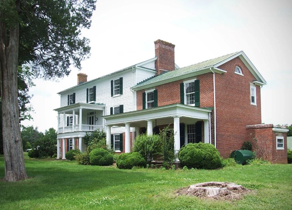 Image of Hyde Park's main house. The structure is a mix of Greek Revival and Federal style architecture. The earliest part of the house is brick, with white wood-paneled additions visible in the picture.