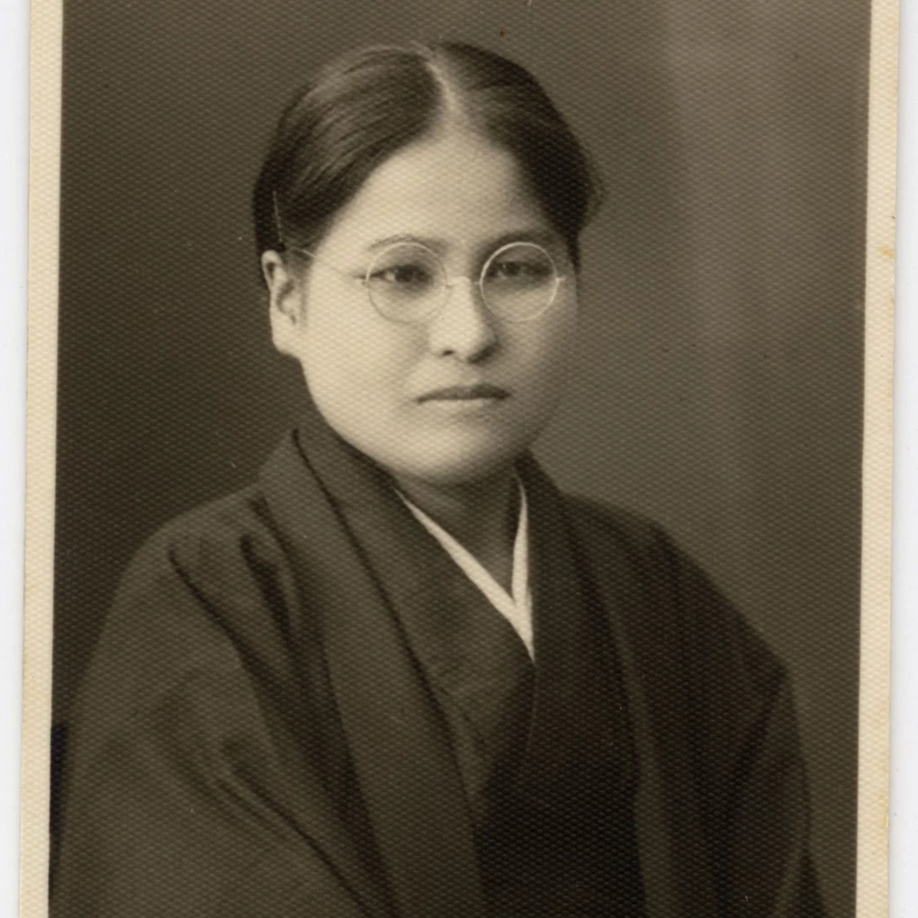 Sepia photo of woman of Japanese descent in wire rim glasses and a dark kimono.