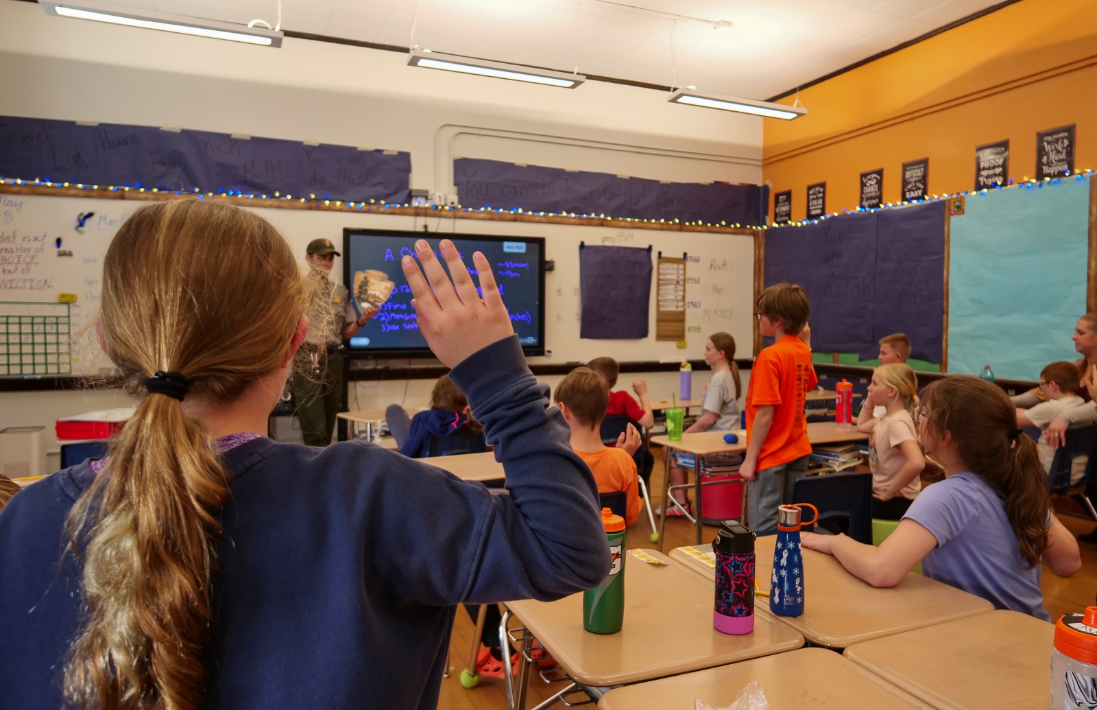 A student raises their hand in a classroom during a ranger-led activity. A student raises their hand in a classroom during a ranger-led activity.