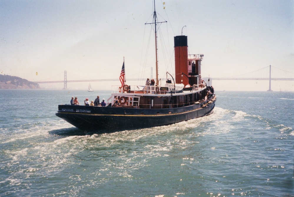 red and black steam-powered tugboat on bay with golden gate bridge in background red and black steam-powered tugboat on bay with golden gate bridge in background