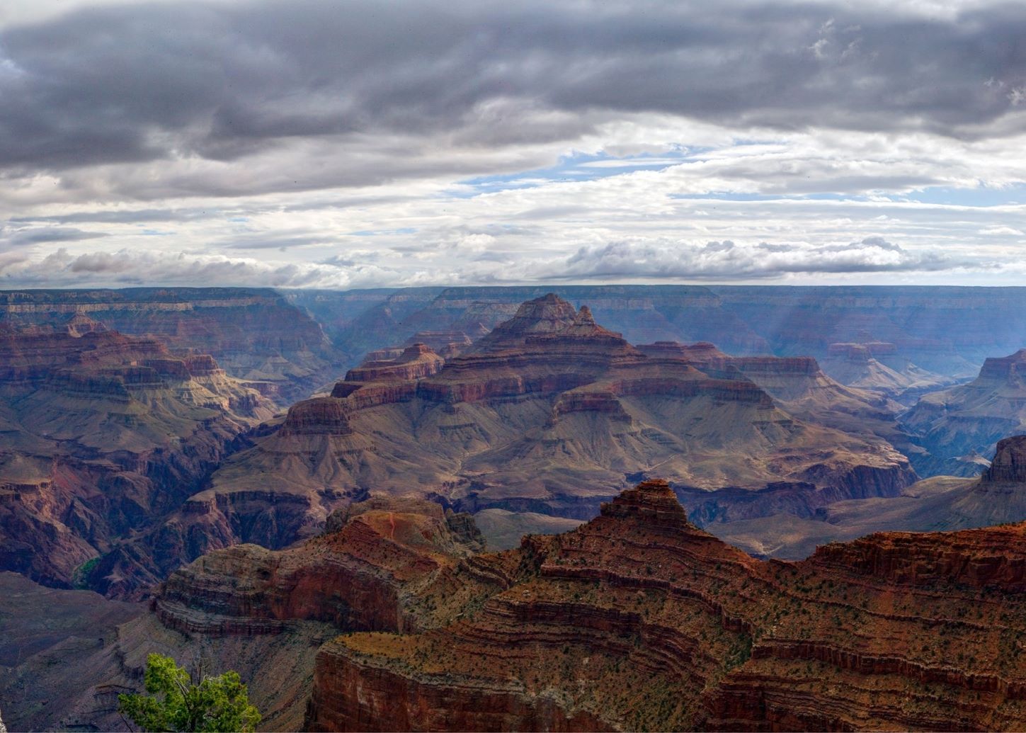 An expansive canyon of red and tan rock on a cloudy day.