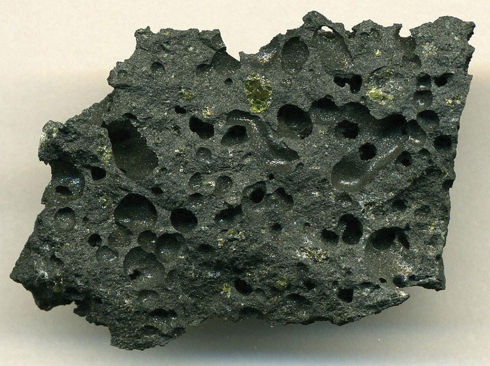 Photo of a dark lava rock with large air holes.