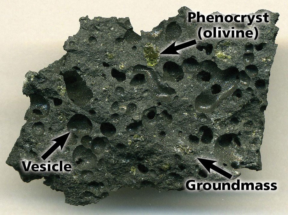 Photo of a dark lava rock with large air holes.