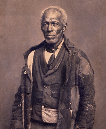 Photograph of George Roberts, wearing tattered cloak