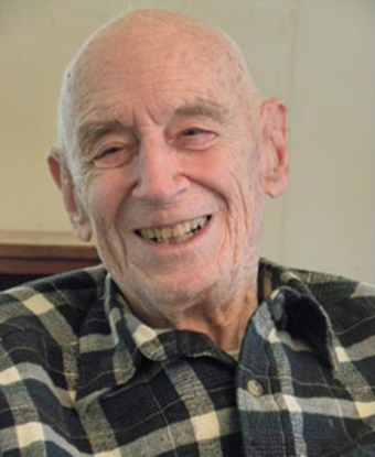 Image of Bill Thies smiling at camera. He is an older gentleman wearing a plaid shirt