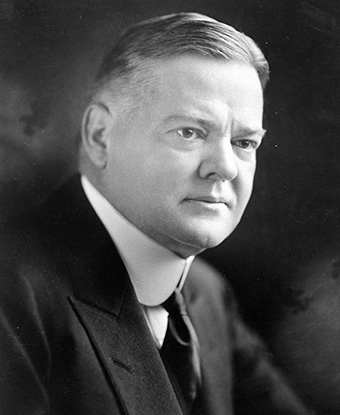 A black and white portrait photo depicts a clean-shaven middle-aged man in a suit. A black and white portrait photo depicts a clean-shaven middle-aged man in a suit.