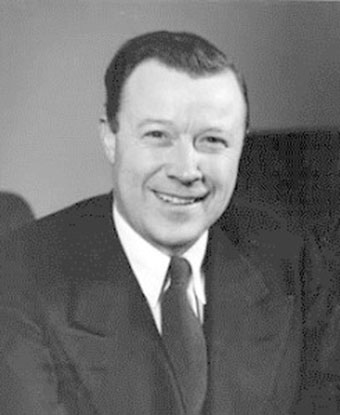 B&W portrait of Mr. Ruether seated, smiling, wearing a suite