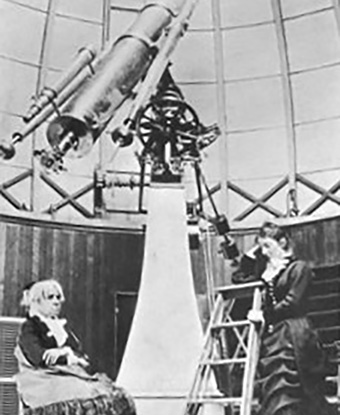 Two women working at a large telescope