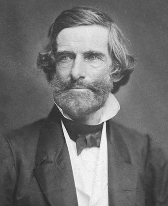 White man wearing a dark suit and tie. He has a full beard and moustache White man wearing a dark suit and tie. He has a full beard and moustache