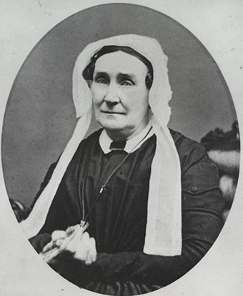 Black and white image of an older woman with brown hair tucked neatly under a white bonnet.