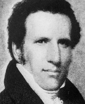 Black and white bust-length portrait of a man with dark hair, wearing a high white collar.