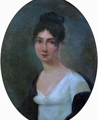 Color image of a torso-length portrait of a young woman with dark hair pulled up on top of her head.