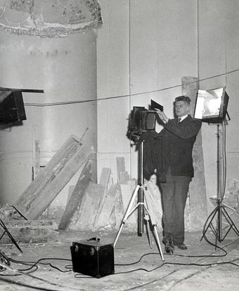 Black and white image of man photographing interior renovation of a building