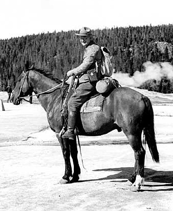 Historic photo of park ranger on horseback near geyser