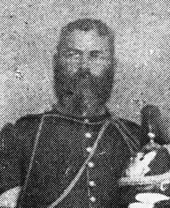 A soldier wearing a dark colored uniform and holding a helmet