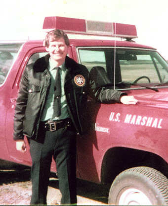Uniformed officer stands next to a bright red patrol vehicle