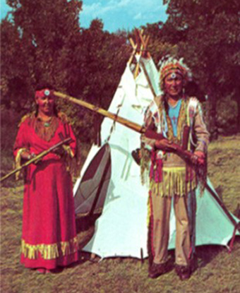 George and Clara in front of a tipi holding a large pipe