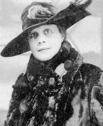 A woman wearing a large hat with feathers and a fur coat