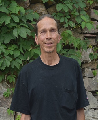 Lean man in black shirt smiling at camera