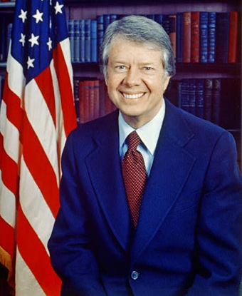 Jimmy Carter, head-and-shoulders portrait, facing front, next to an American flag