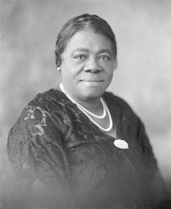 Head and shoulder portrait of a woman in a dress and a double strand of pearls.