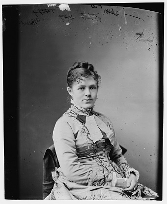 Woman sitting in chair and wearing a large hoop dress.