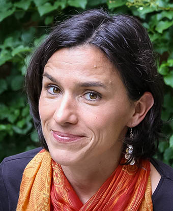 Woman wearing an orange scarf in front of a leafy background
