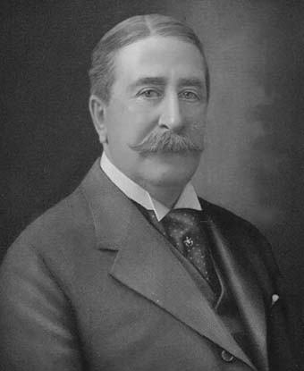 A black and white head and shoulders photograph of a man wearing a suit.