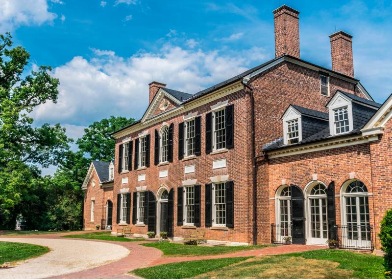 A stately red brick manor stands proud in the sunlight