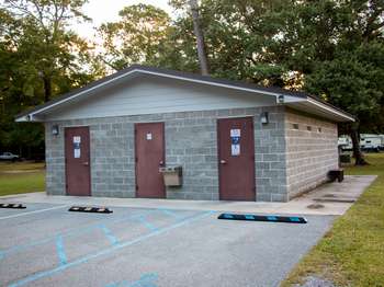 Light brown cement building with a brown roof. Three brown metal doors in the side of the building.