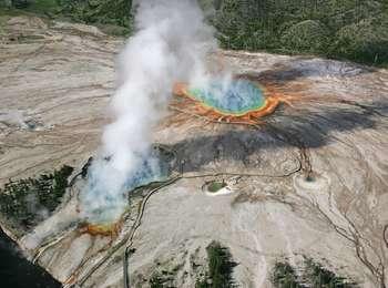 An aerial view of four steaming, colorful hot springs connected by boardwalks