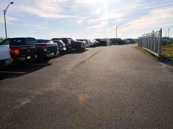 Beachgoersâ€™ cars and trucks line the parking lot on a hot summer day.
