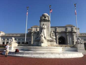 A large circular fountain with a statue of Christopher Columbus in the middle