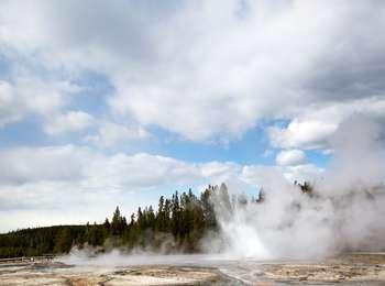 Steam and water erupt from a small geyser