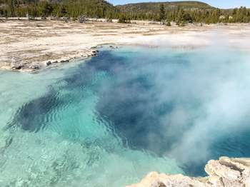 Close-up showing the deep, blue water and hot steam of the hot spring.