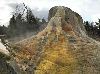 A steaming orange, yellow, green, and white, travertine mound